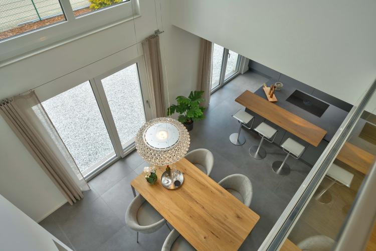Blick von der Galerie im Obergeschoss auf Essplatz und Küche: Der Luftraum unterstreicht die Großzügigkeit der Planung. <i>Foto: HELMA Eigenheimbau AG</i>
