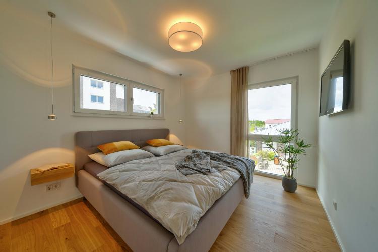  Puristisches Wohlfühlambiente im elterlichen Schlafzimmer.<i> Foto: HELMA Eigenheimbau AG</i><br>