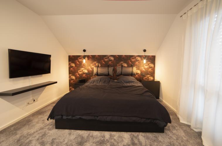 Das Schlafzimmer wirkt mit einem ausgelegten Teppich sehr gemütlich. Die Rückenlehne hat sie selbst erstellt. <i>Foto: HELMA Eigenheimbau AG / Ralph Thiele</i>