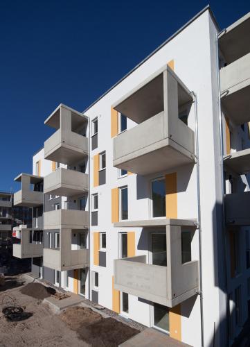 Jede Wohnung verfügt entweder über Terrasse oder Balkon. Die Farbgestaltung in Weiß, Orange und Grau rhythmisiert die Fassade. Die weit auskragenden Balkone vergrößern die Mietflächen, reflektieren den Umgebungsschall und erhöhen so den Wohnkomfort. <i>Foto: Deutsche Poroton / Heinz Heister</i>